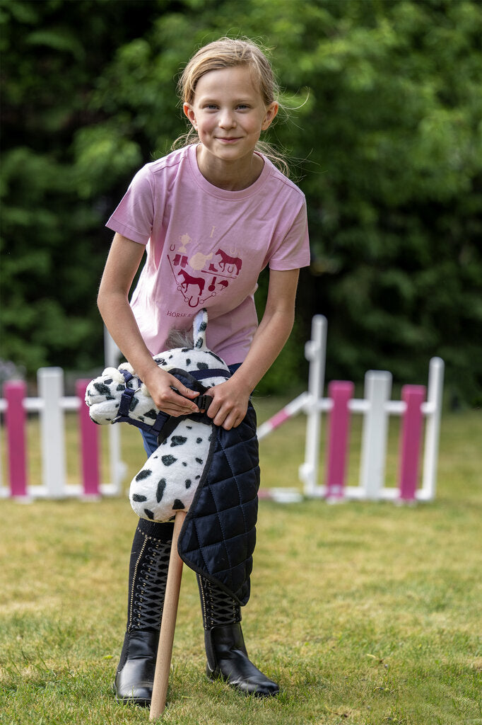 Mädchen legt ihrem Hobby Horse eine blaue Decke an – liebevoller Moment mit Steckenpferd