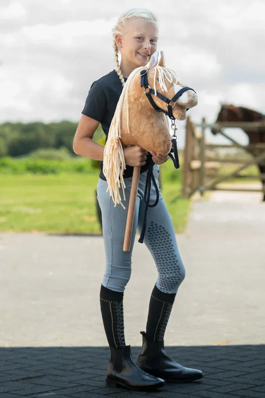 Mädchen zeigt stolz ihr Hobby Horse mit Halfter und Strick