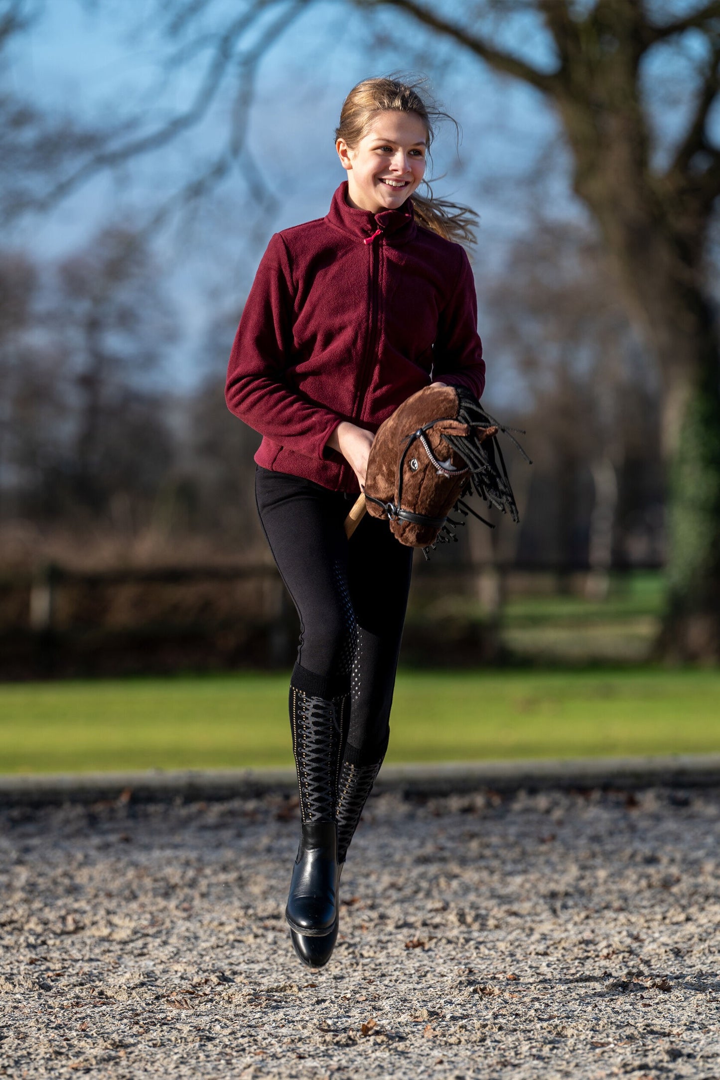 Mädchen galoppiert mit braunem Hobby Horse
