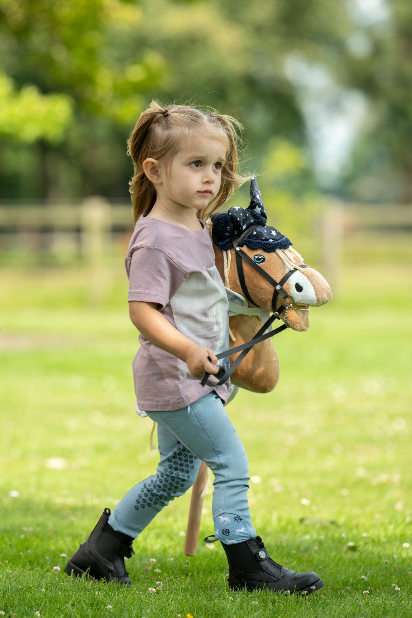 Kleines Mädchen führt ihr Palomino Hobby Horse spazieren
