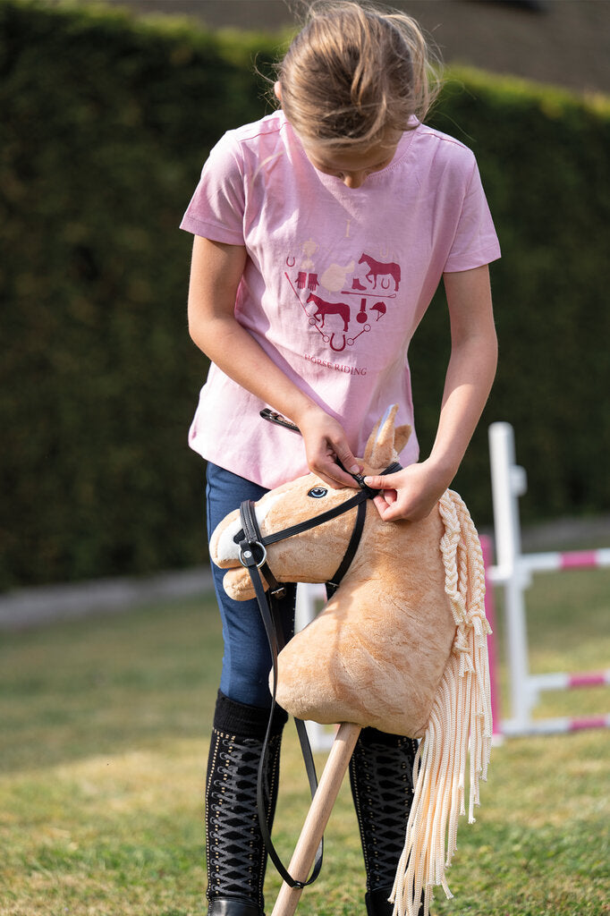 Mädchen mit rosa Shirt wechselt Stirnriemen an Hobby Horse Trense in schwarz