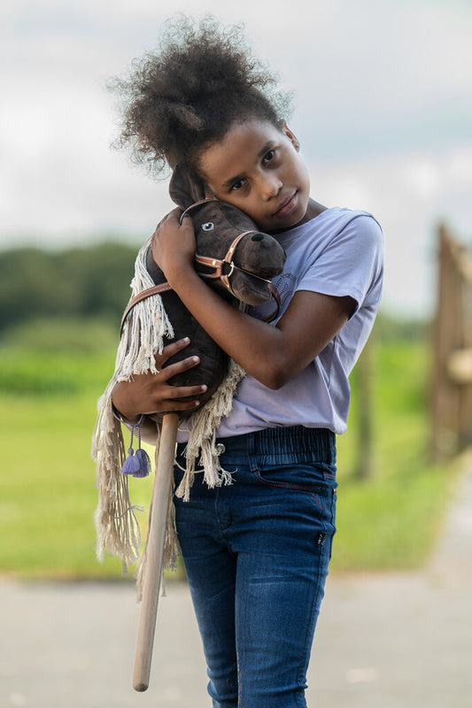 Mädchen kuschelt mit braunem Hobby Horse
