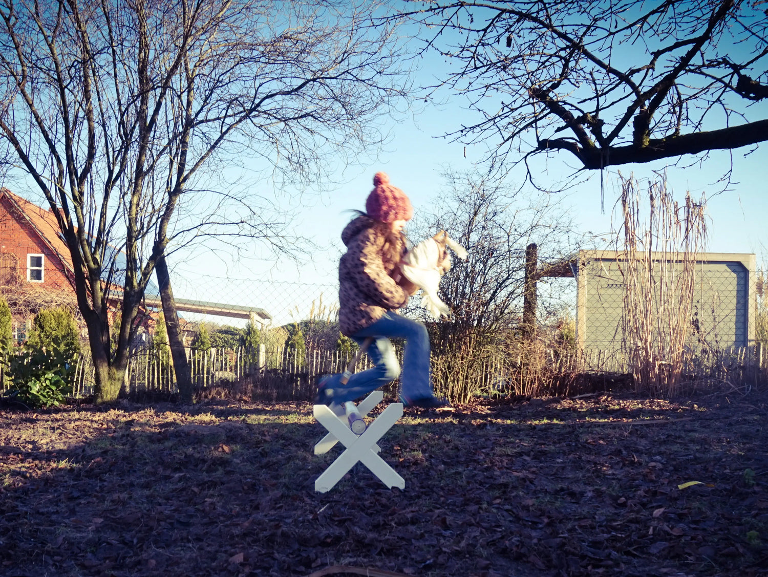 Ein Mädchen springt in der Morgensonne mit ihrem Hobby Horse über ein Cavaletti