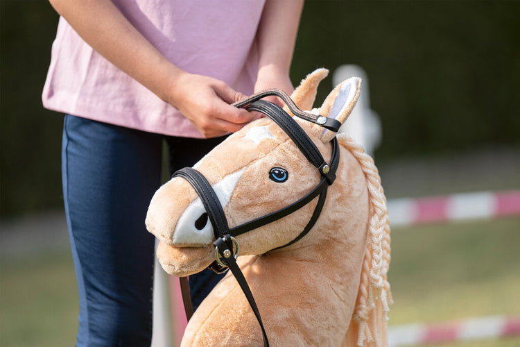 Mädchen legt einem Hobby Horse eine Trense an – Zubehör für Steckenpferd-Fans