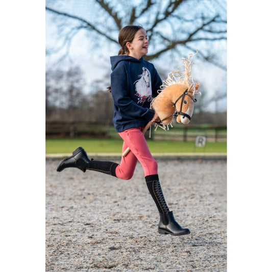 Maedchen reitet auf Hobby Horse mit schwarzer Trense