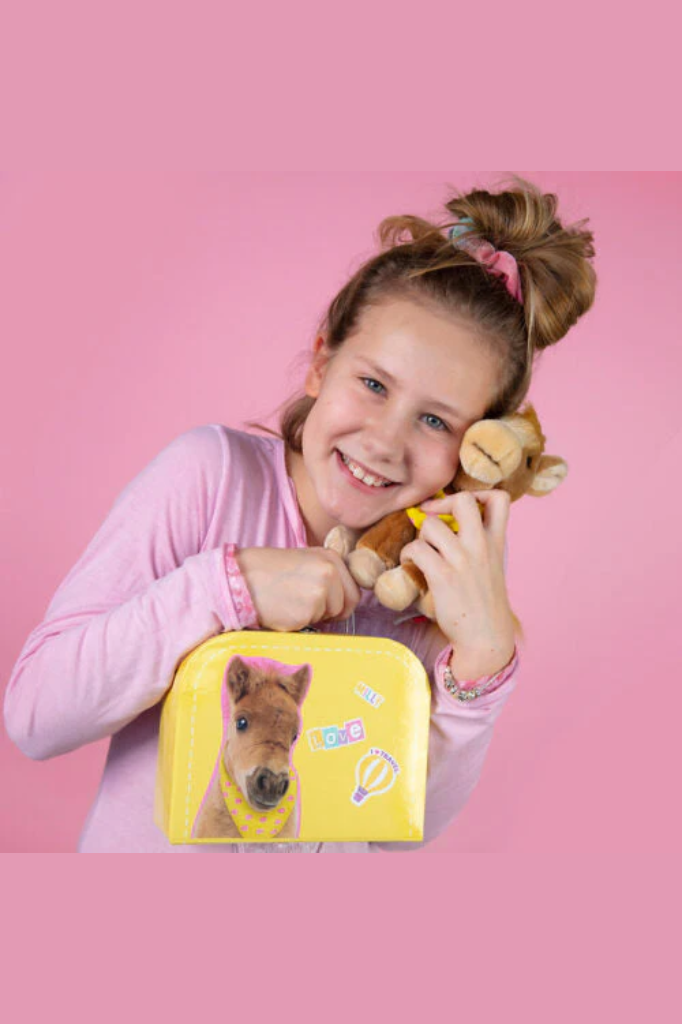 Kuscheltierpferd sitzend mit gelben Halsband wird von einem Mädchen mit hohem Dutt gekuschelt