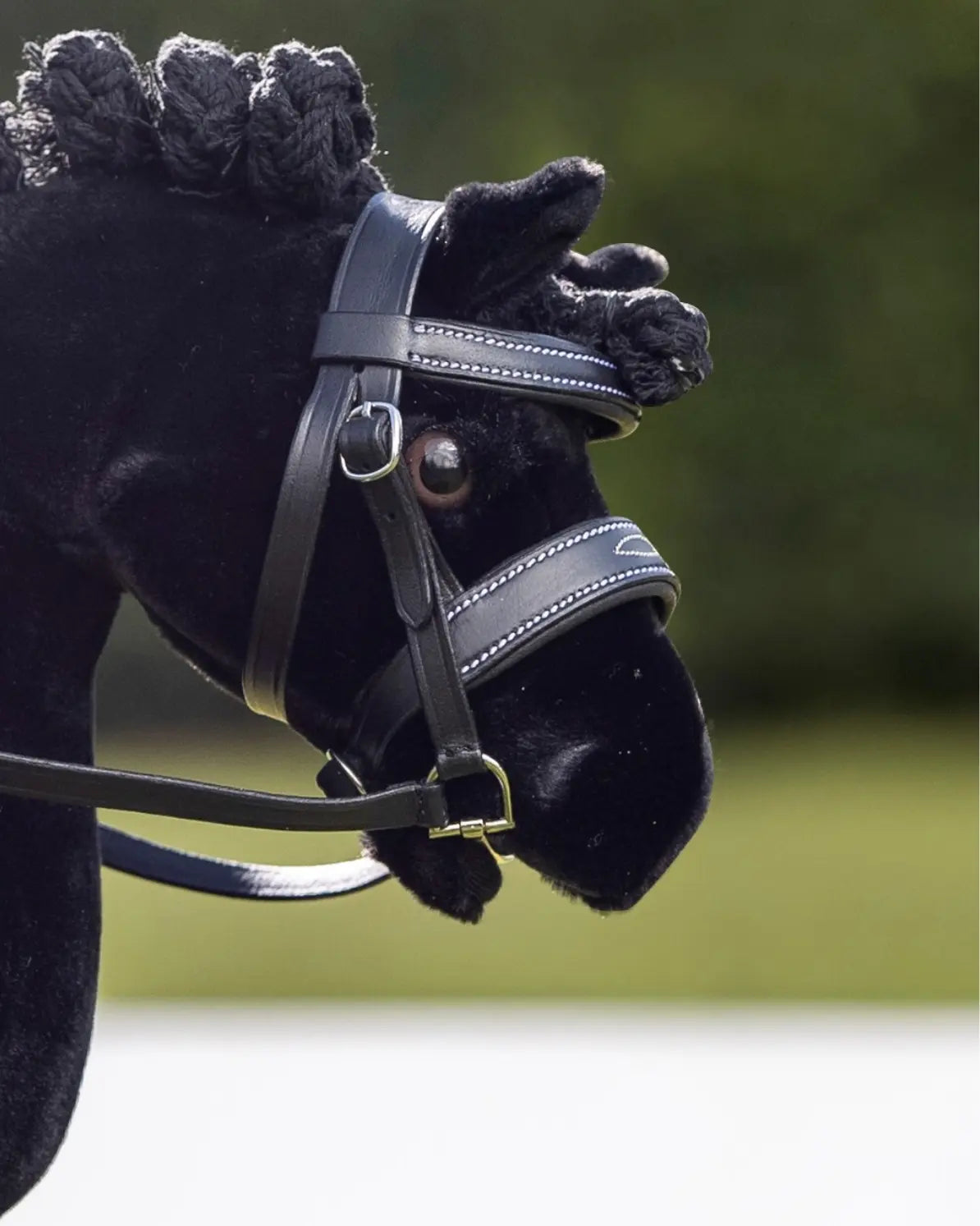 Klassische Turnieroptik fürs Hobby Horsing: Ein schwarzes Steckenpferd präsentiert die schwarze LeMieux Turniertrense – ideal passend für die Modelle der HKM Professional Slim Line.