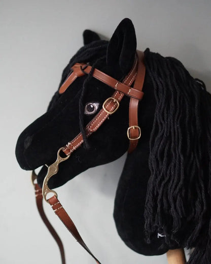 Ein schwarzes Hobby Horse trägt die  braune LeMieux Westerntrense mit verzierter Kandare.