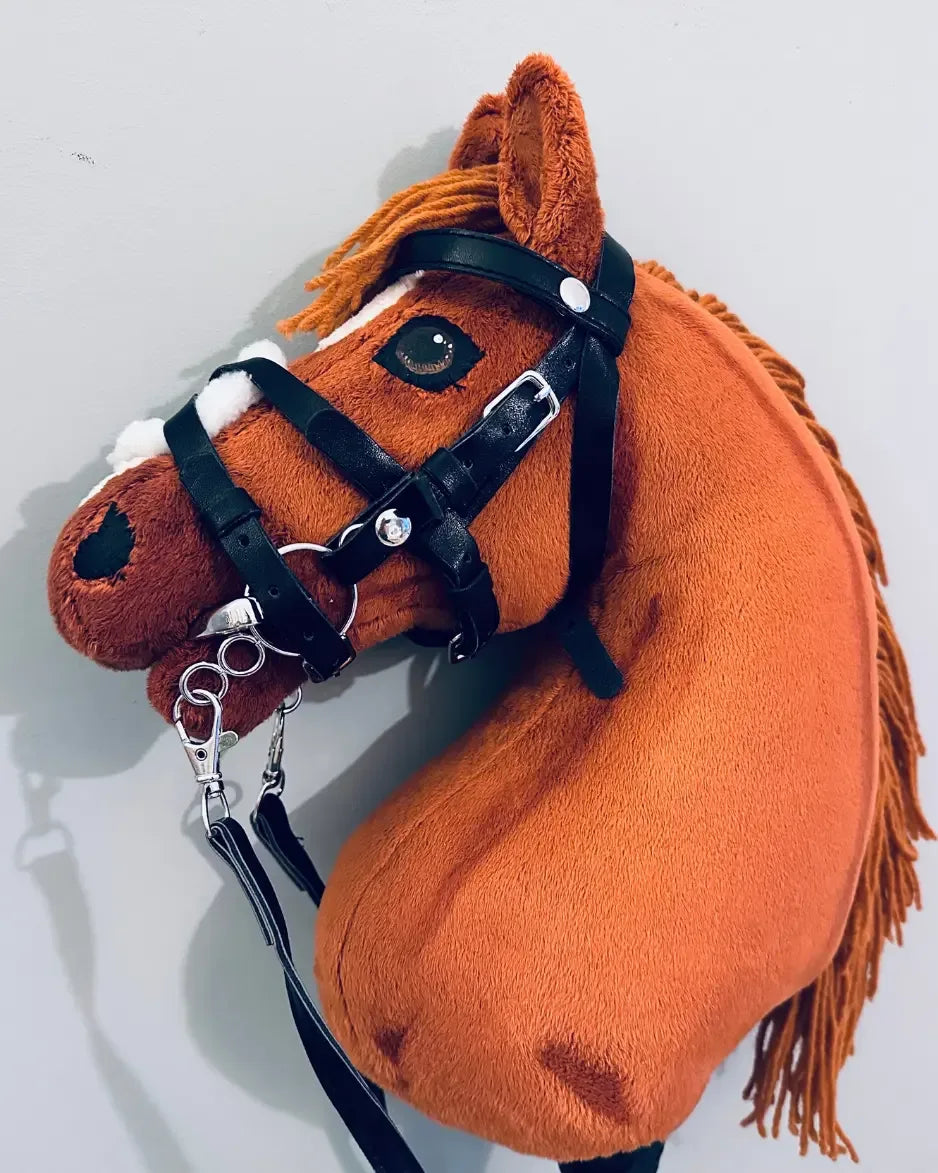 Seitenaufnahme eines fuchsfarbenen, finnisches Hobby Horses aus einer DIY Hobby Horse Ponybox, dass eine schwarze Panduro Hobby Horse Trense trägt in die ein Panduro Hobby Horse Gebiss eingeschnallt ist.