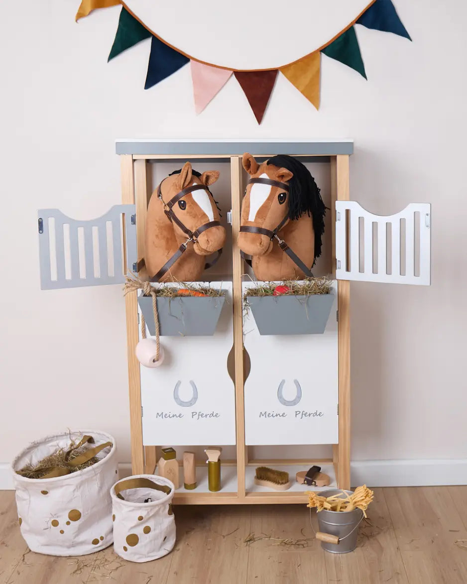 Zwei Bieco Steckenpferde in einem Spielzeug-Pferdestall mit Heu; ideal für Rollenspiele im Kinderzimmer
