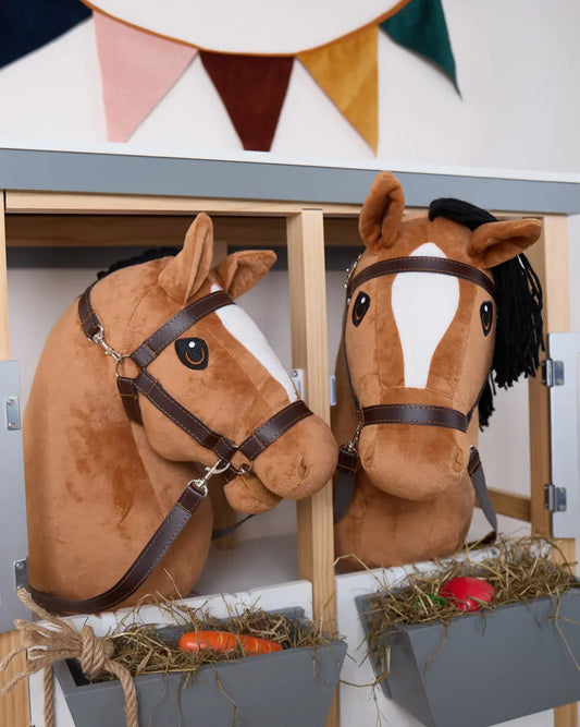 Detailaufnahme von zwei Hobby Horses mit Halfter im Stall; hochwertiges Spielzeugpferd für Rollenspiel und Hobby Horsing