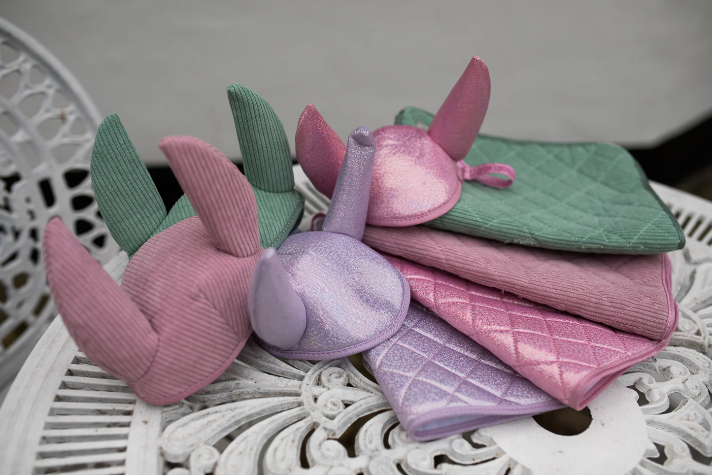 Hobby Horsing Set ByAstrup in rosa und lila mit Decke und Fliegenhaube gestapelt auf einem Gartentisch