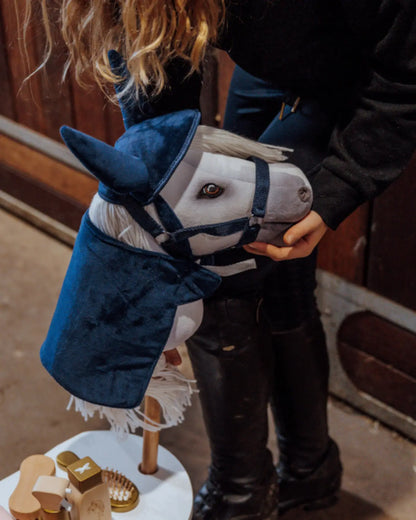 Mädchen hält ein weißes Hobby Horse mit dunkelblauem byASTRUP Samt-Set Cosy aus Decke und Fliegenohren.