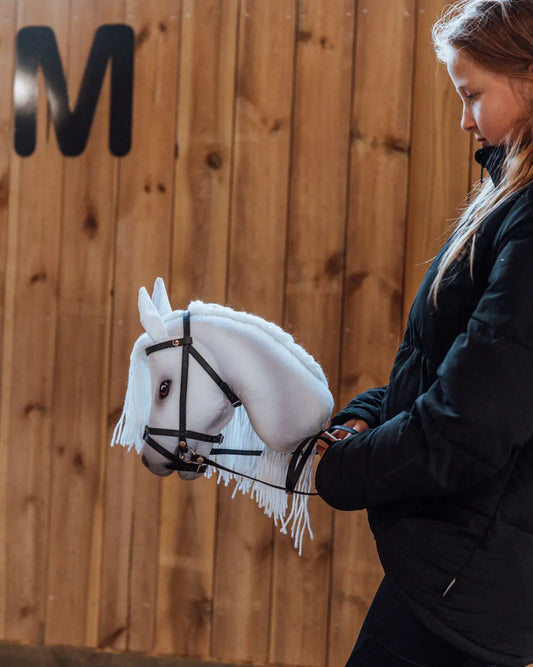 Mädchen hält das weiße byASTRUP Hobby Horse Sigrid in Größe M für vielseitigen Spielspaß bei Indoor- und Outdoor-Abenteuern.