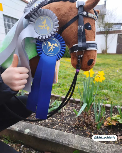 Braunes Dressur Hobby Horse zum selbermache gewinnt drei Schleifen und trägt eine Panduro Turniertrense in schwarz
