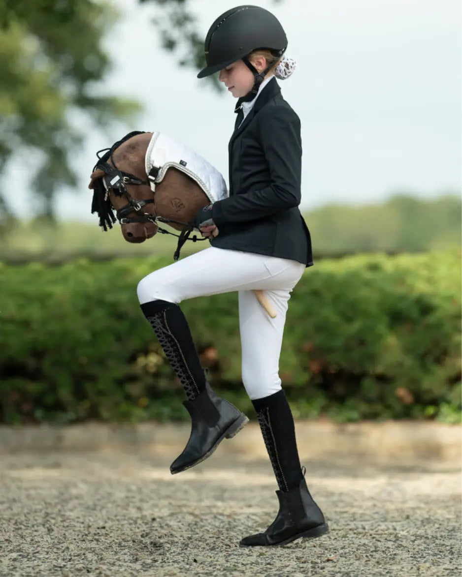 Professionelles Hobby Horsing Turnierzubehör: Ein Mädchen in klassischer Reitbekleidung übt mit dem HKM Steckenpferd „Avalon“ anspruchsvolle Dressurschritte im Freien.
