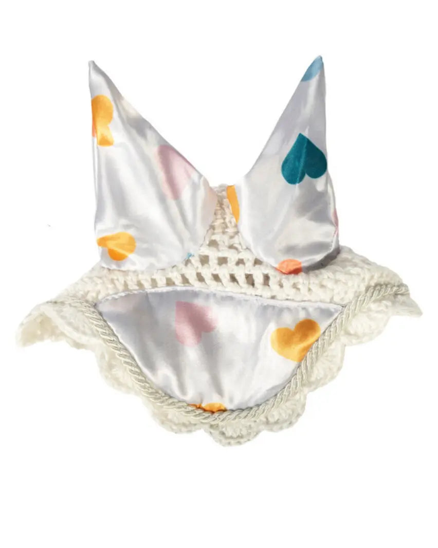 Fliegenohren/Fliegenhaube für ein Hobby Horse der Marke HKM für ein Hobby Horse in einer freigestellten Aufnahme. die Fliegenhaube ist weiß mit bunten, große, Herzen