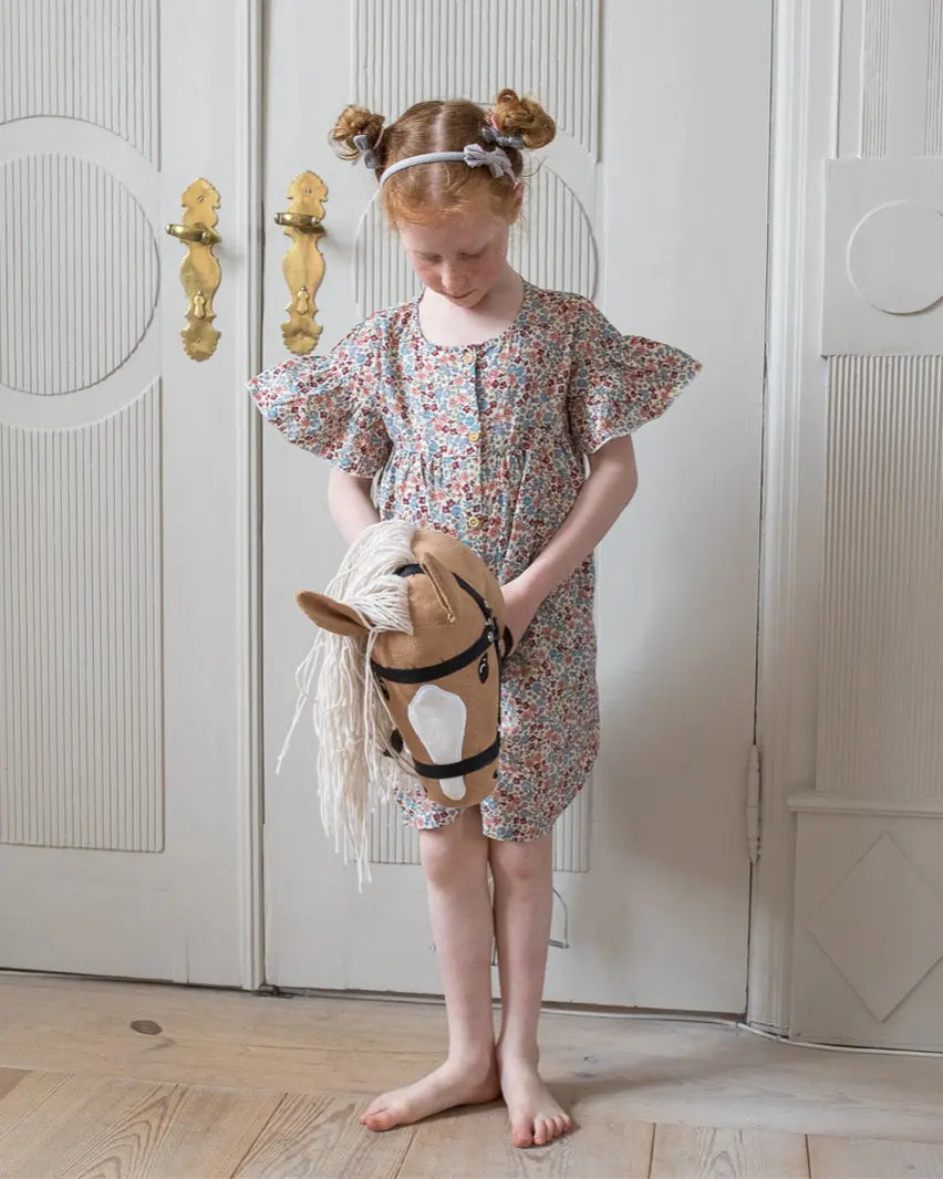 Premium Holzspielzeug von byASTRUP: Mädchen präsentiert stolz ihr Palomino Hobby Horse mit weißer Blesse – die perfekte Geschenkidee für Kinder ab 3 Jahren.