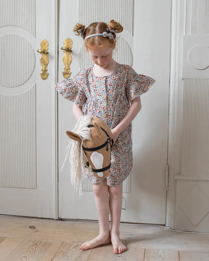 Premium Holzspielzeug von byASTRUP: Mädchen präsentiert stolz ihr Palomino Hobby Horse mit weißer Blesse – die perfekte Geschenkidee für Kinder ab 3 Jahren.