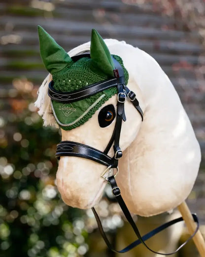 Realistisches Reitsport-Design im Miniaturformat: Ein Palomino Hobby Horse präsentiert die dunkelgrüne LeMieux Fliegenhaube Hunter Green bei einer Präsentation im Garten.