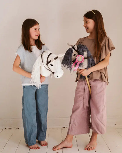 Fantasievolles Rollenspiel im Kinderzimmer: Zwei Mädchen vergleichen ihre byASTRUP Hobby Horses (ein weißes und ein graues Modell) mit Trense.
