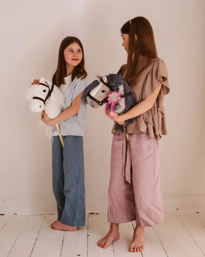 Aktive Bewegung und Spielspaß: Kinder spielen gemeinsam mit ihren leichten byASTRUP Steckenpferden aus robustem Pappelholz und Polyester.