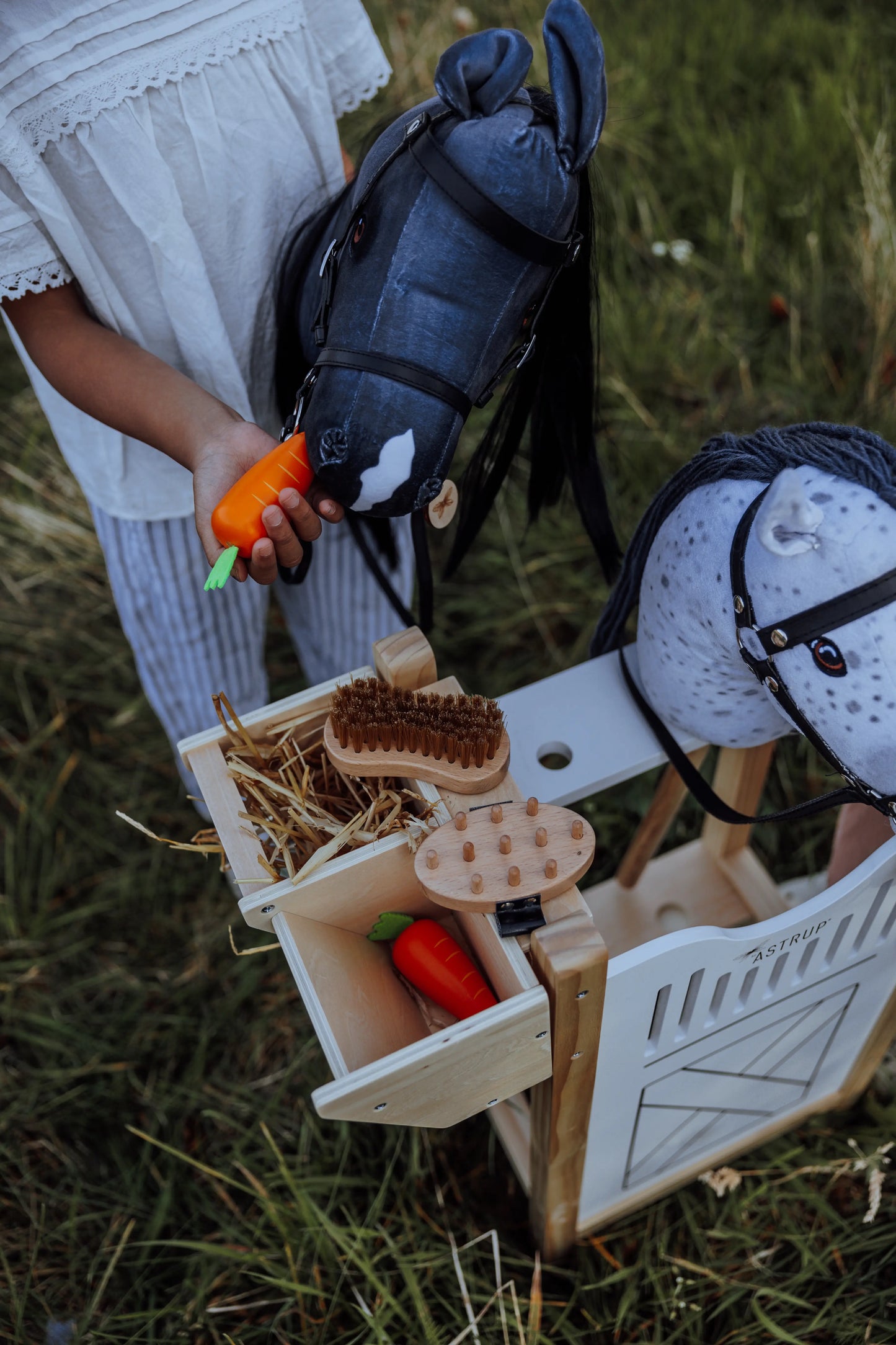 Kinder füttern und pflegen ihre Steckenpferde im stabilen byASTRUP Hobby Horse Stall – ideal für langlebigen Spielspaß.