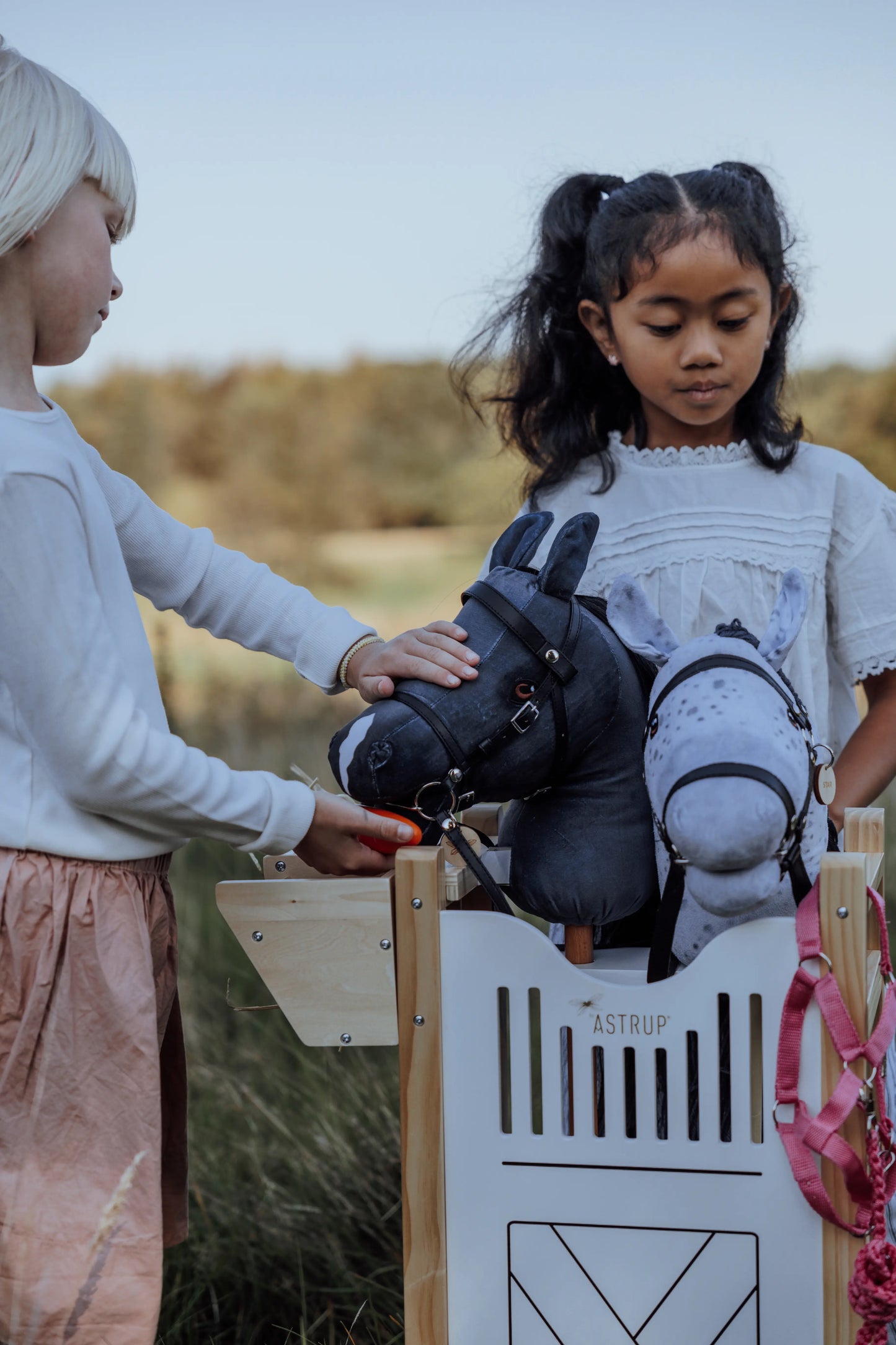 Gemeinsamer Spielspaß beim Hobby Horsing: Kinder organisieren ihr Steckenpferd-Zubehör wie Trensen und Decken direkt am großen byASTRUP Holzstall.