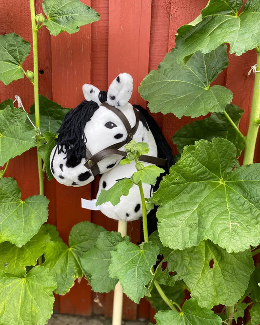 Das punktierte byASTRUP Steckenpferd dekorativ im Garten platziert – ein Muss für kreatives Outdoorspiel und Hobby Horsing Fans.