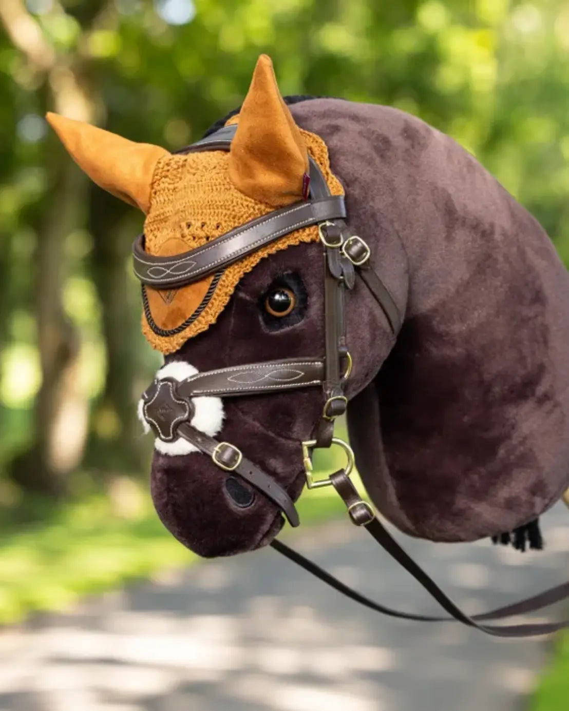 lemieux hobby horse fliegenohren in ocker/ginger an einem dunkelbraunem lemieux hobby horse, dass eine dunkelbraune mexikanische hobby horse trense trägt.