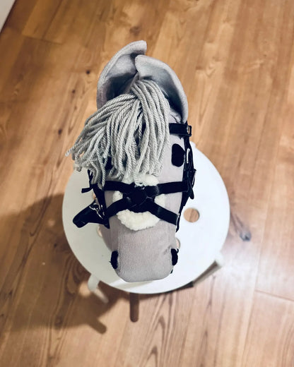 Aufnahme eines finnischen, hellgrauen Hobby Horses, dass eine schwarze Panduro Hobby Horse Trense trägt. Die Trense hat ein Reithalfter im mexikanischem Stil und ist weich unterlegt.